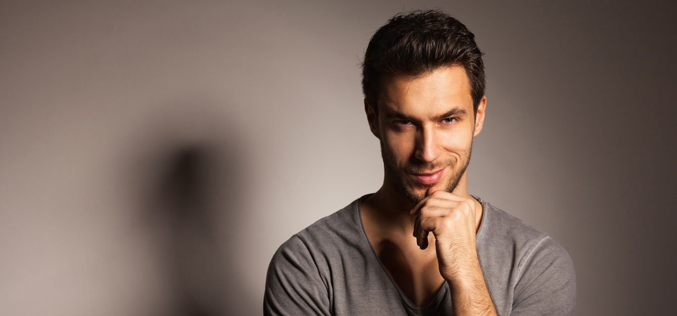 homem branco com barba e mão no queixo com visual harmonico após ter feito preenchimento facial masculino