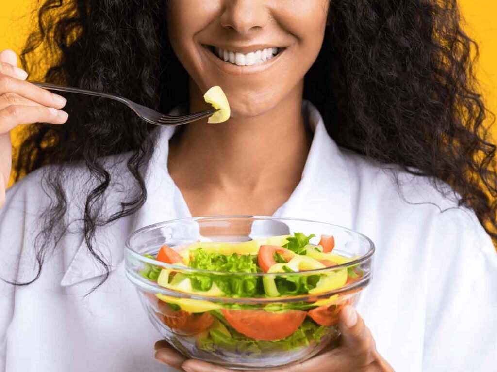 mulher negra com cabelos cacheados faz refeição saudável após reeducação alimentar